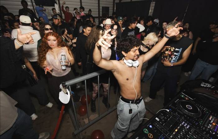 The DJ leaning off the rail into the crowd, headphones around his neck